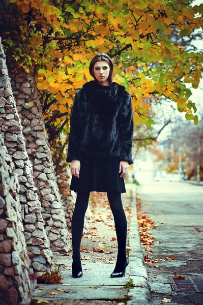 Mujer joven de moda posando cerca de una pared de piedra — Foto de Stock