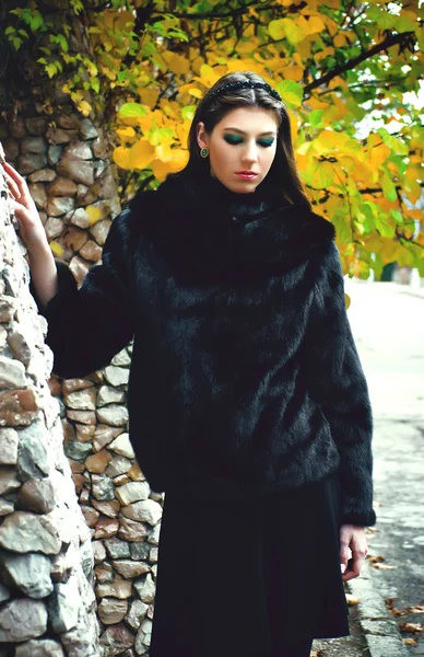 Giovane donna alla moda in posa vicino a un muro di pietra — Foto Stock