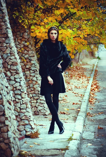 Fashionable young woman posing near a stone wall — Stock Photo, Image