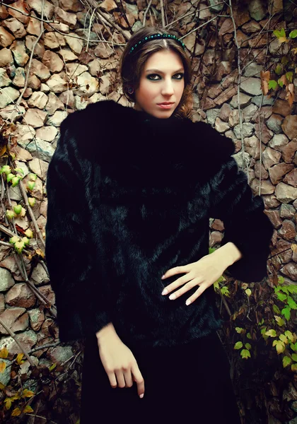 Fashionable young woman posing near a stone wall — Stock Photo, Image