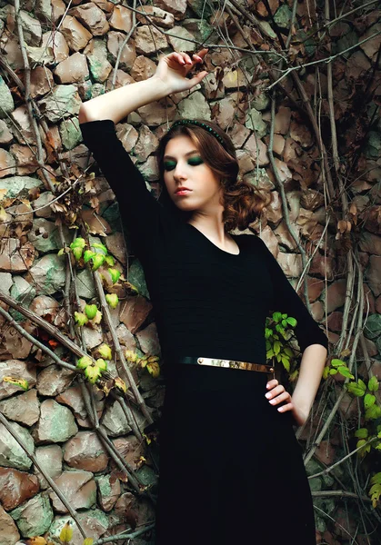 Mujer joven de moda posando cerca de una pared de piedra —  Fotos de Stock