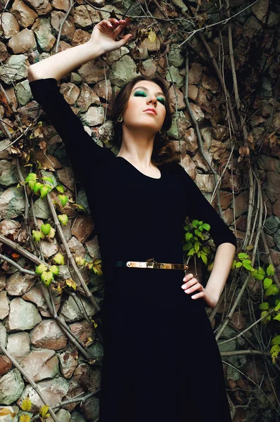 Mujer joven de moda posando cerca de una pared de piedra — Foto de Stock