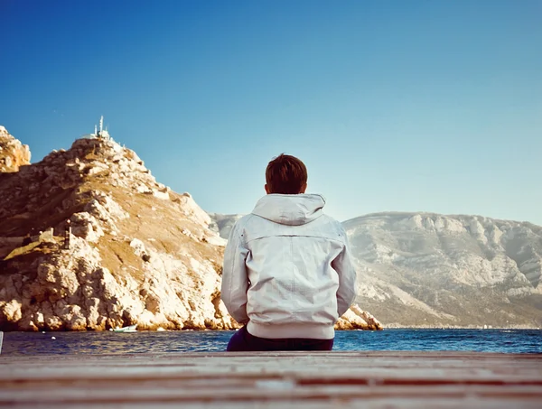 Lonely young man sitting on the dock — Stock Photo, Image