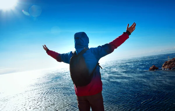 Ung man står på ett berg med armarna upp — Stockfoto