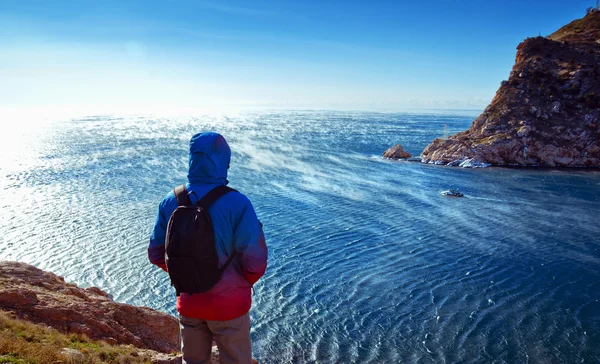 Young man stands on a hill on a background of the sea — Stock Photo, Image