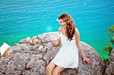 Güzel kız bir tepede denize bir arka plan üzerinde oturur