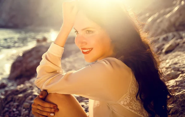 Beautiful young girl sitting on the beach alone — Stock Photo, Image