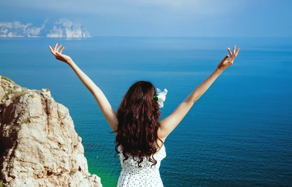 Beautiful girl looks at the sea with his arms raised — Stock Photo, Image