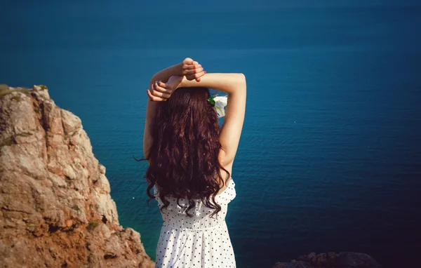 Beautiful girl looks at the sea with his arms raised — Stock Photo, Image