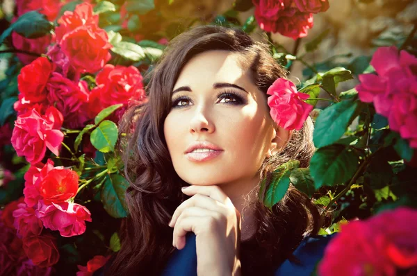 Ritratto di una giovane bella donna tra le rose in fiore — Foto Stock
