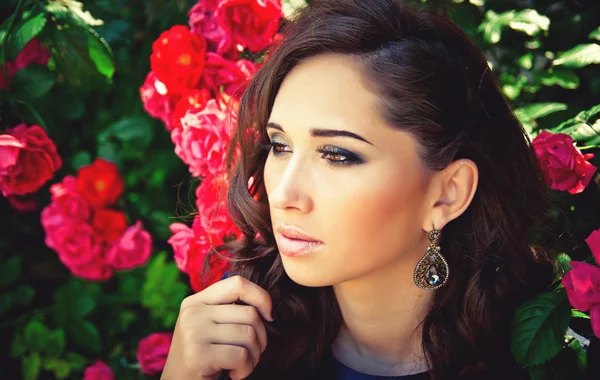 Ritratto di una giovane bella donna tra le rose in fiore — Foto Stock