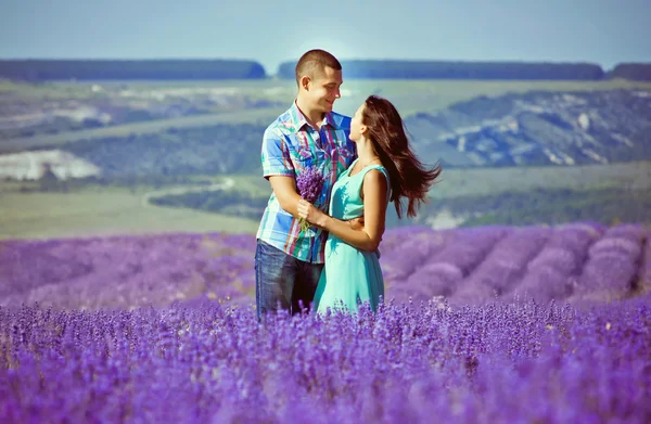 Joven pareja atractiva en un campo en verano — Foto de Stock