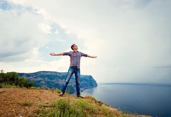 Kerel op de top van een berg met uitgestrekte armen — Stockfoto