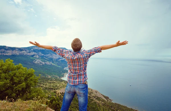 Kerel op de top van een berg met uitgestrekte armen — Stockfoto