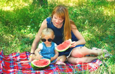 genç anne ve çocuk parkta oturan karpuz yeme