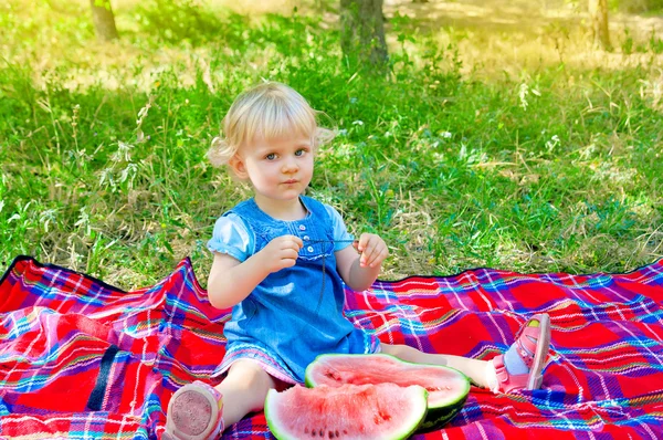 Roztomilá holčička, sedí v parku s meloun — Stock fotografie