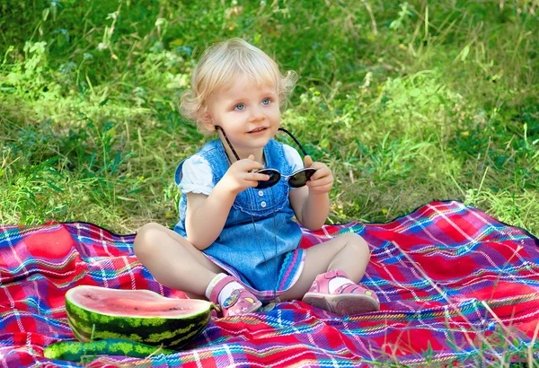 Kleines süßes Mädchen sitzt im Park mit Wassermelone — Stockfoto