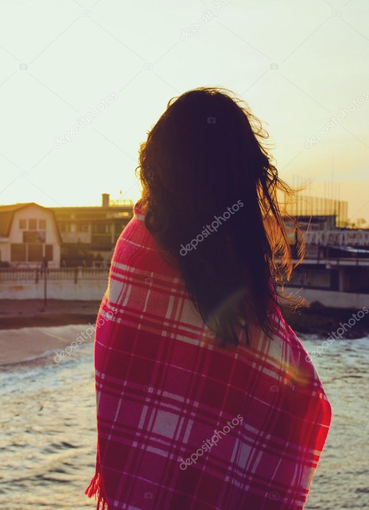 attractive girl standing near the sea wrapped in a blanket