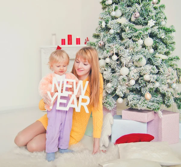 Jonge moeder met baby in de buurt van de kerstboom — Stockfoto