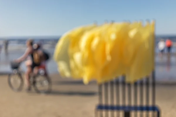 Bandeiras amarelas e ciclista na praia. Desfoque — Fotografia de Stock