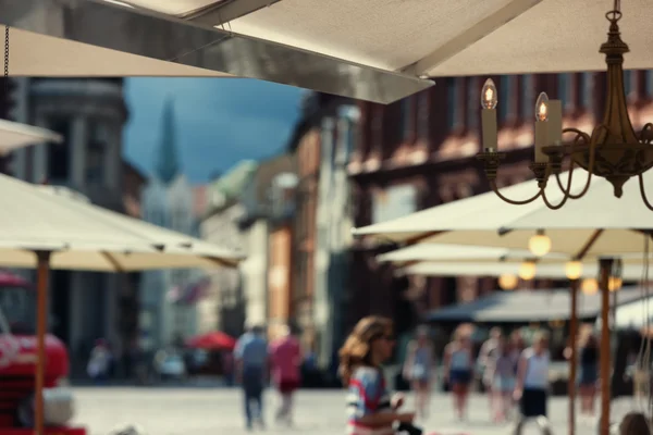 Guarda-chuvas ao ar livre cafés e turistas na praça em Riga — Fotografia de Stock