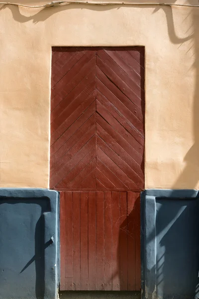 Porta vermelha pintada na parede laranja — Fotografia de Stock