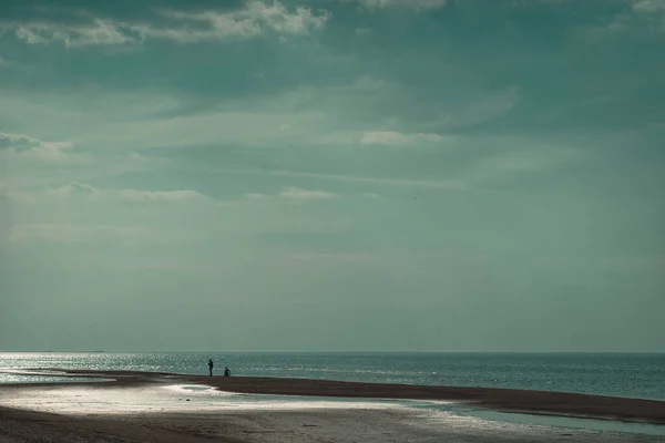 海の上のビーチで孤独な人 近くに自転車があります ラトビアの砂浜で晴れた日に春の散歩 — ストック写真