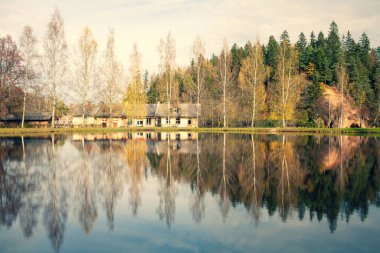 Göl kenarındaki ağaçlı kum kayaları yansımalı.