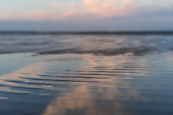 La playa en la marea alta al atardecer con reflejo de nubes — Foto de Stock