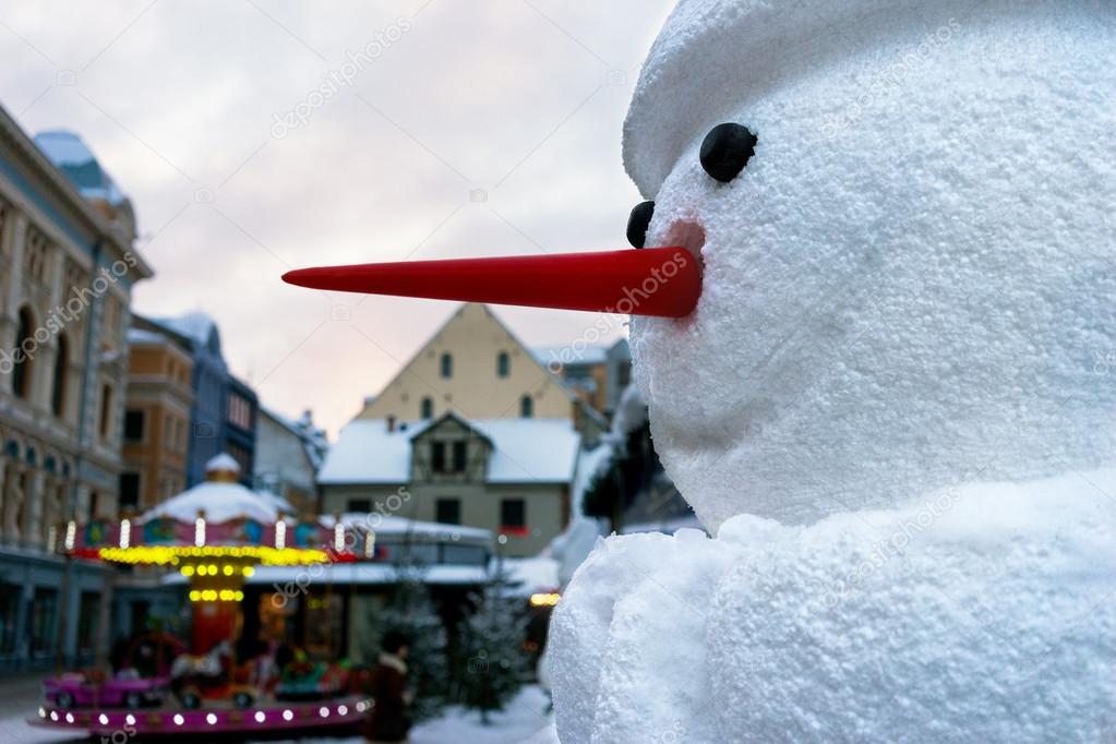 Snowman with a red nose in the city on Christmas and New Year