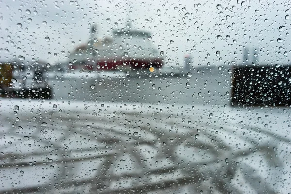 Nave en el puerto a través de las gotas de lluvia sobre vidrio en una fuerte nieve — Foto de Stock