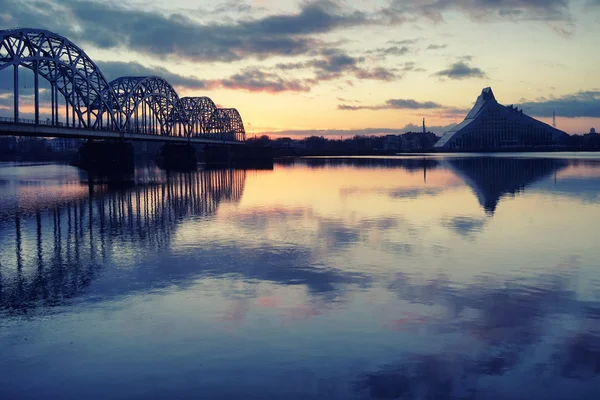Латвийская национальная библиотека на железнодорожном мосту на закате — стоковое фото