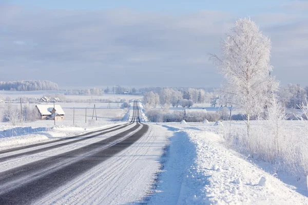 Linee asfalto strada invernale attraverso il campo rurale all'orizzonte — Foto Stock