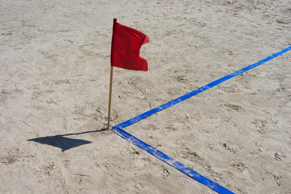 Aire de jeux d'angle sur la plage avec ruban bleu et drapeau rouge — Photo