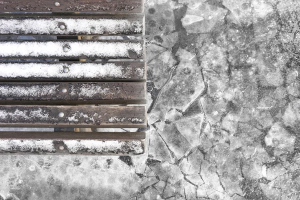 Bench with snow on the background of ice in winter park — Stock Photo, Image