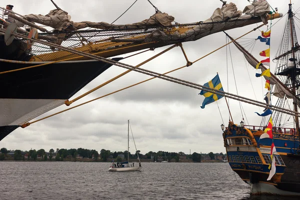 Вітрильні човни з прапорами біля причалу і човна на воді — стокове фото