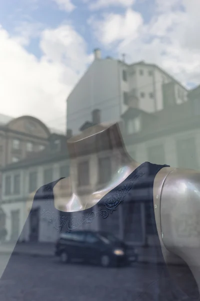 Las casas se reflejan en la ventana con un maniquí en un vestido — Foto de Stock