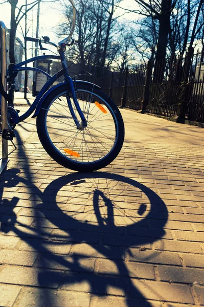 Bike with orange reflector at the fence of the park — Stock Photo, Image