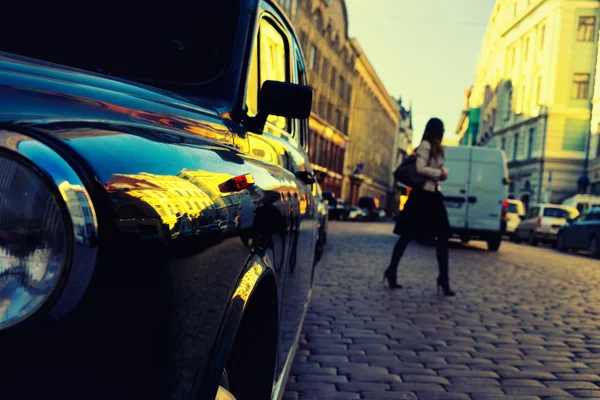 Menina cruzando a estrada de pedras entre os carros na cidade — Fotografia de Stock