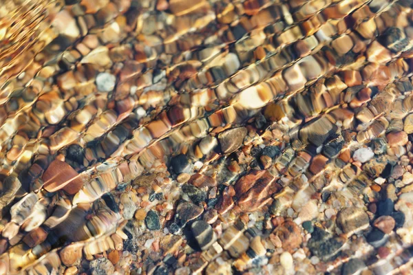 Piedras en el fondo del mar a través de las pequeñas olas — Foto de Stock