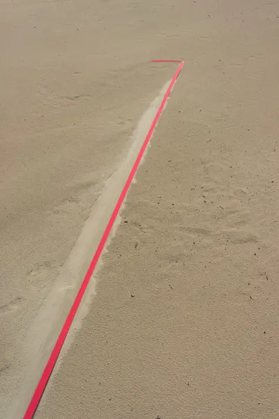 Detalle de una línea roja en la arena después de la lluvia — Foto de Stock