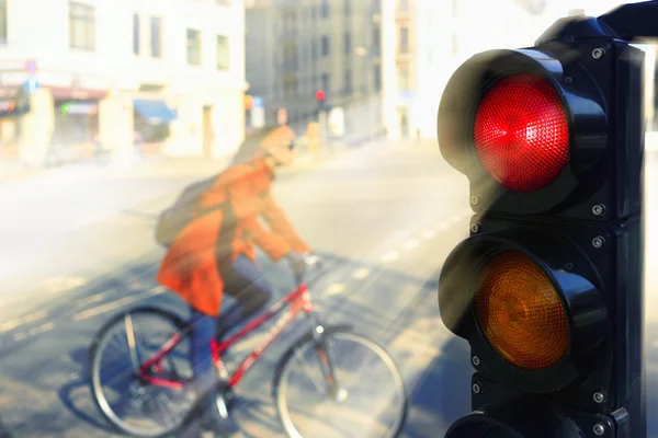 The girl on a bicycle on a city street at a red traffic light — Stock Photo, Image