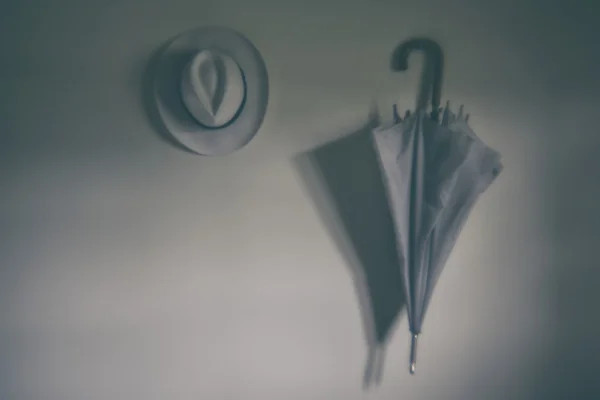 Parapluie blanc et chapeau accroché au mur. Blurry — Photo