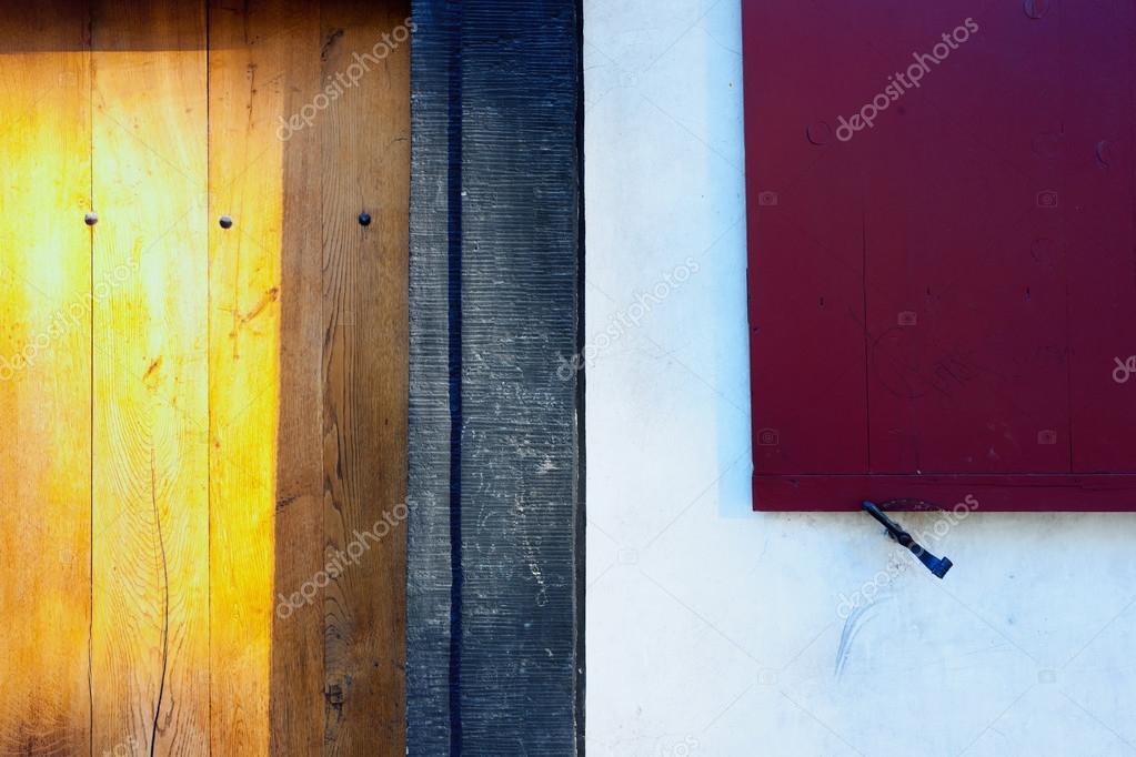 Red Shutters And Yellow Wooden Door Of An Old House Stock Photo
