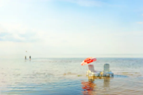 Sillas de cubierta en el mar con un paraguas y un par. Borroso. —  Fotos de Stock