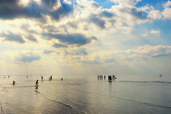 Silhouettes of people walking in the sea after the tide — Stock Photo, Image