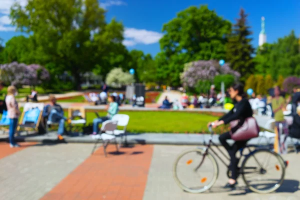 Turister i ljusa sommarkläder promenader i parken i Riga. Suddiga — Stockfoto