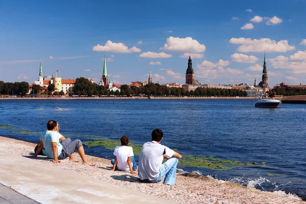 Turistas en la orilla del río en el panorama de fondo Riga —  Fotos de Stock