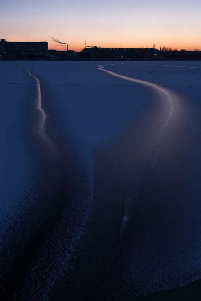 Fissures dans la glace de la rivière dans la ville au coucher du soleil — Photo