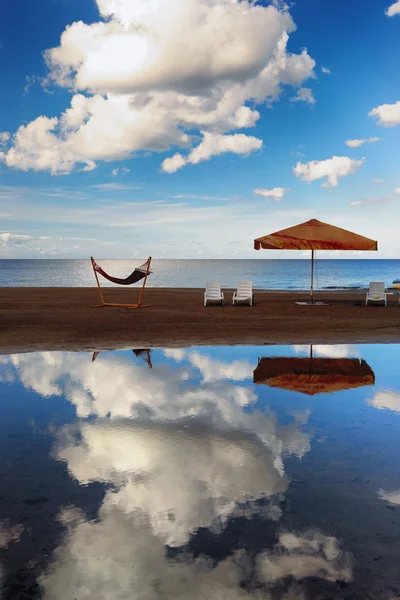 Hängematte mit Sonnenschirm und Stühlen auf einem schmalen Streifen Sand auf — Stockfoto